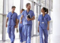 Four healthcare workers in scrubs walking in corridor