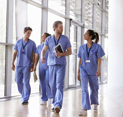 Four healthcare workers in scrubs walking in corridor