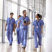 Four healthcare workers in scrubs walking in corridor